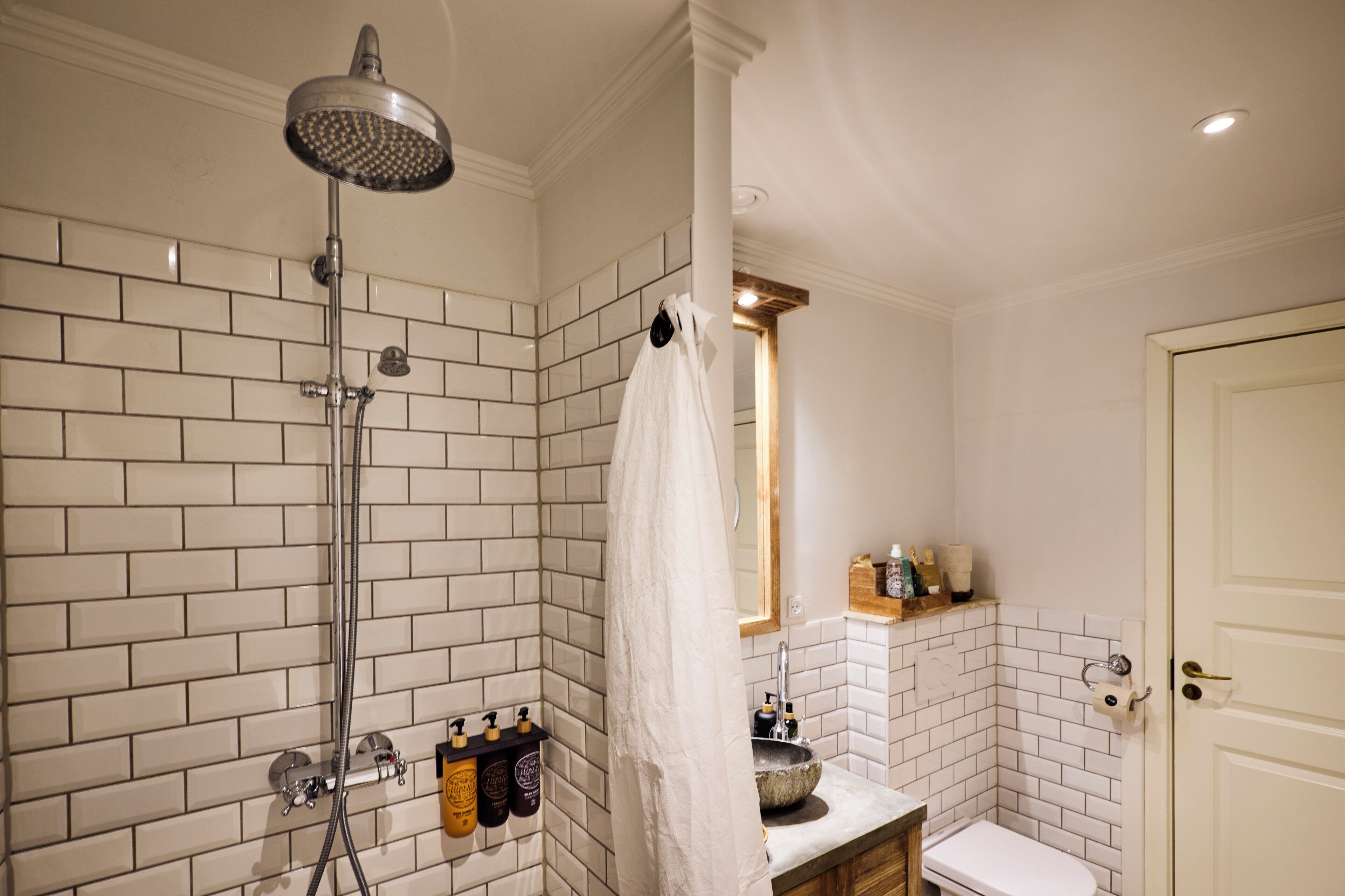 A bathroom with a shower, sink, toilet, and a mirror.