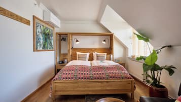 A bedroom with a wooden bed, two bedside lamps, a large window, and a potted plant.