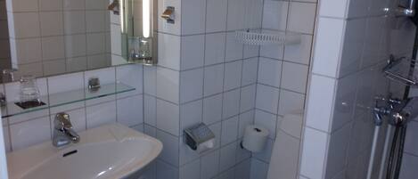A bathroom with a sink, mirror, and shower.