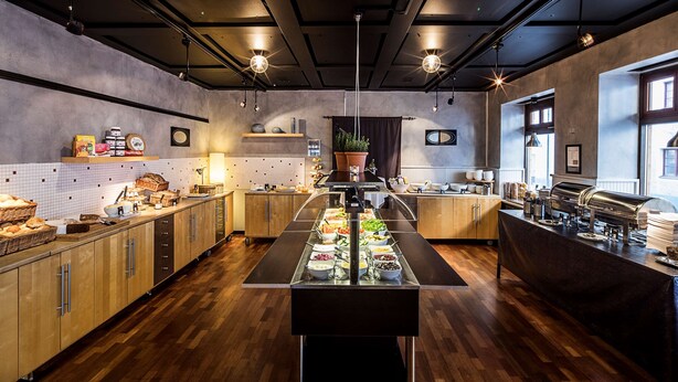 Une cuisine moderne avec des meubles en bois, un îlot central où sont disposés des aliments et un coin café.