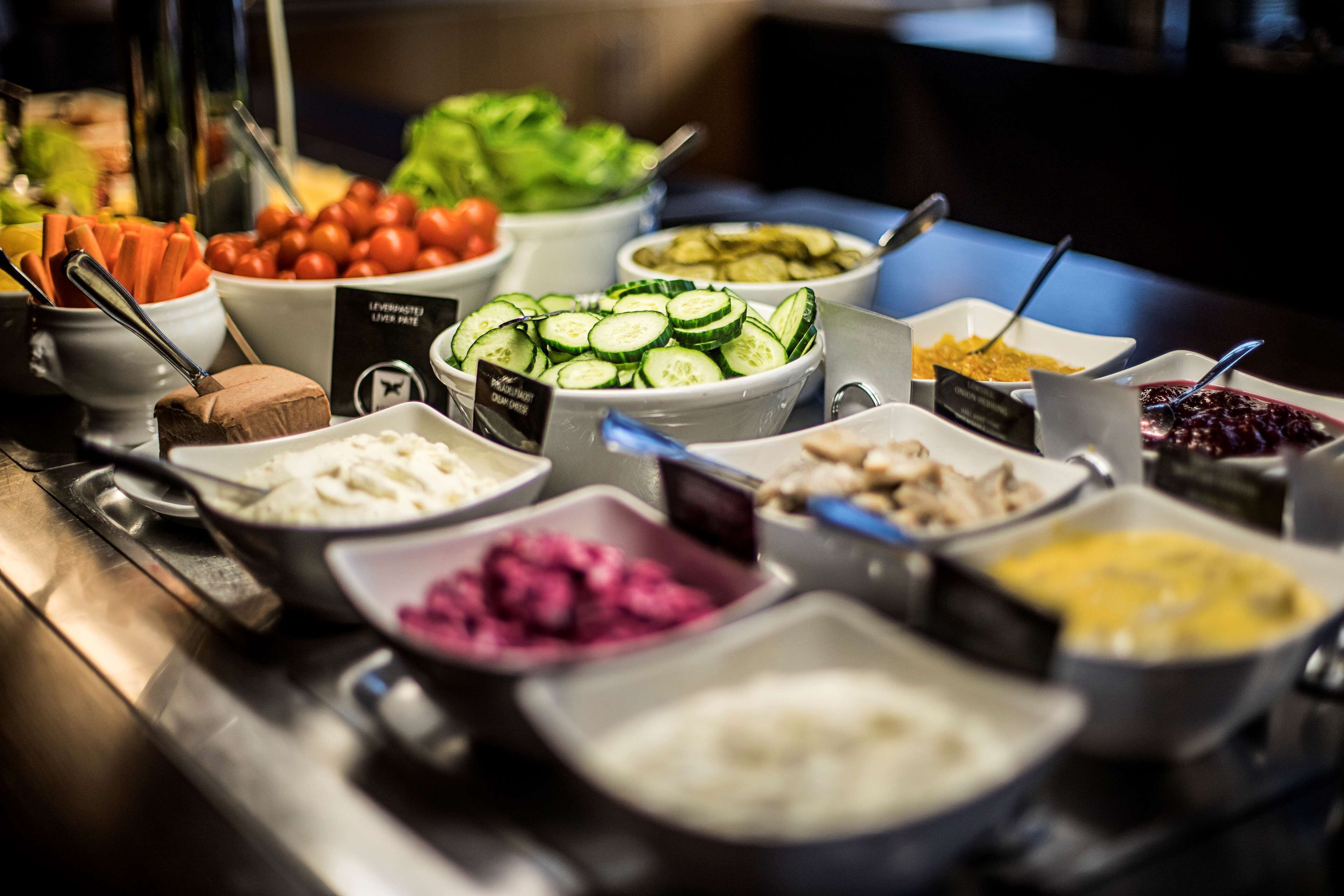 A buffet with various food items including vegetables, fruits, and desserts.
