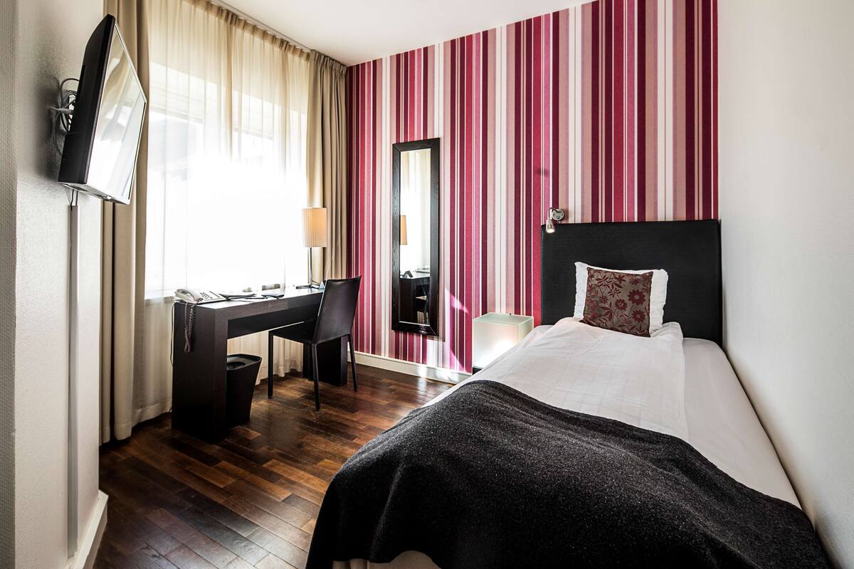 Una habitación de hotel con cama, escritorio, silla y televisor.
