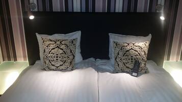 Un lit avec deux coussins décoratifs et une étiquette sur l’un des coussins.