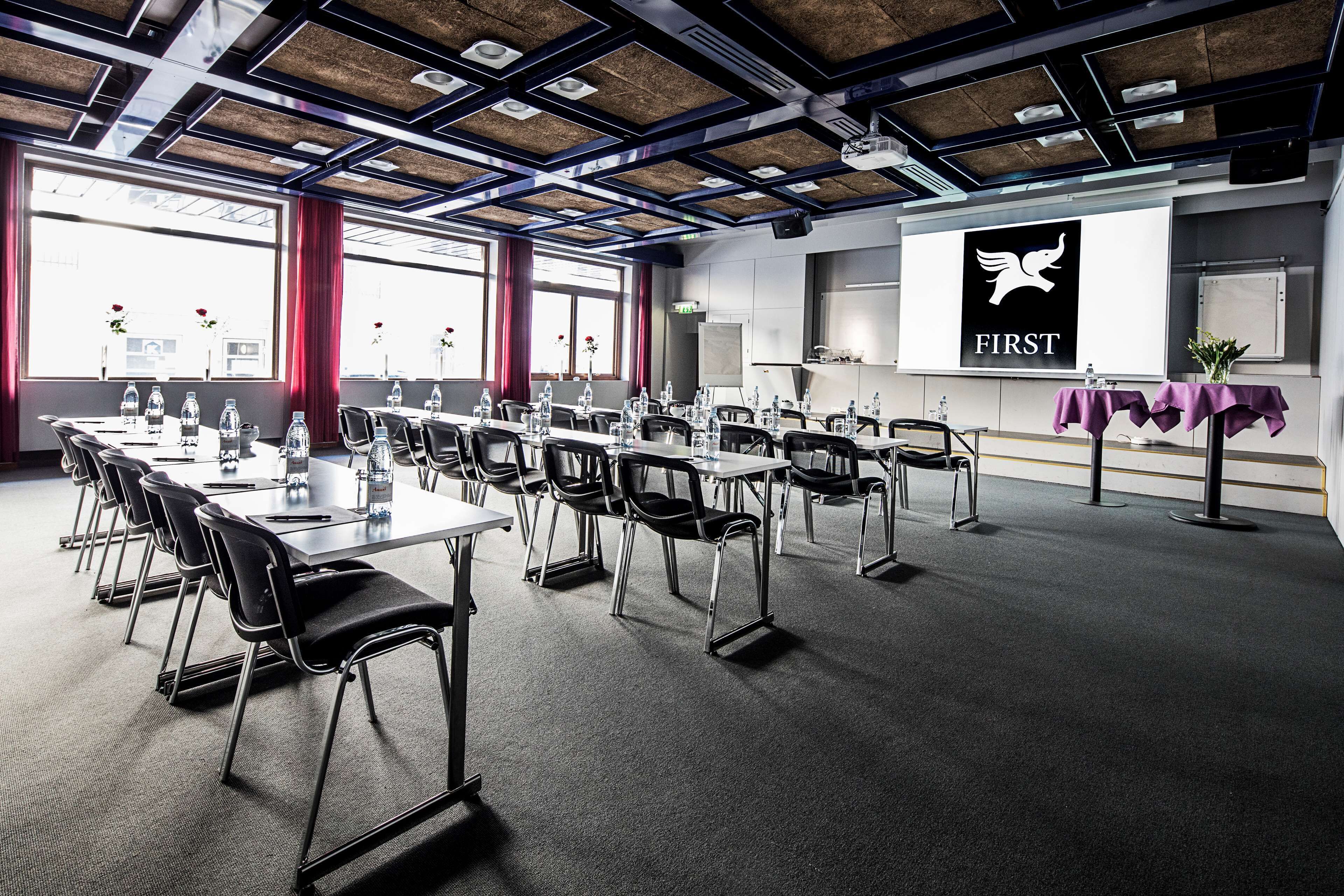 A conference room with a long table, chairs, and a presentation screen.