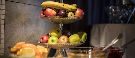 A fruit display with apples, bananas, and oranges on a tiered stand.