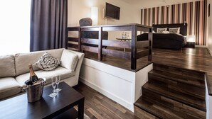 Une chambre d’hôtel moderne équipée d’un canapé, d’une table à manger, d’un téléviseur, d’un lit et d’un escalier.