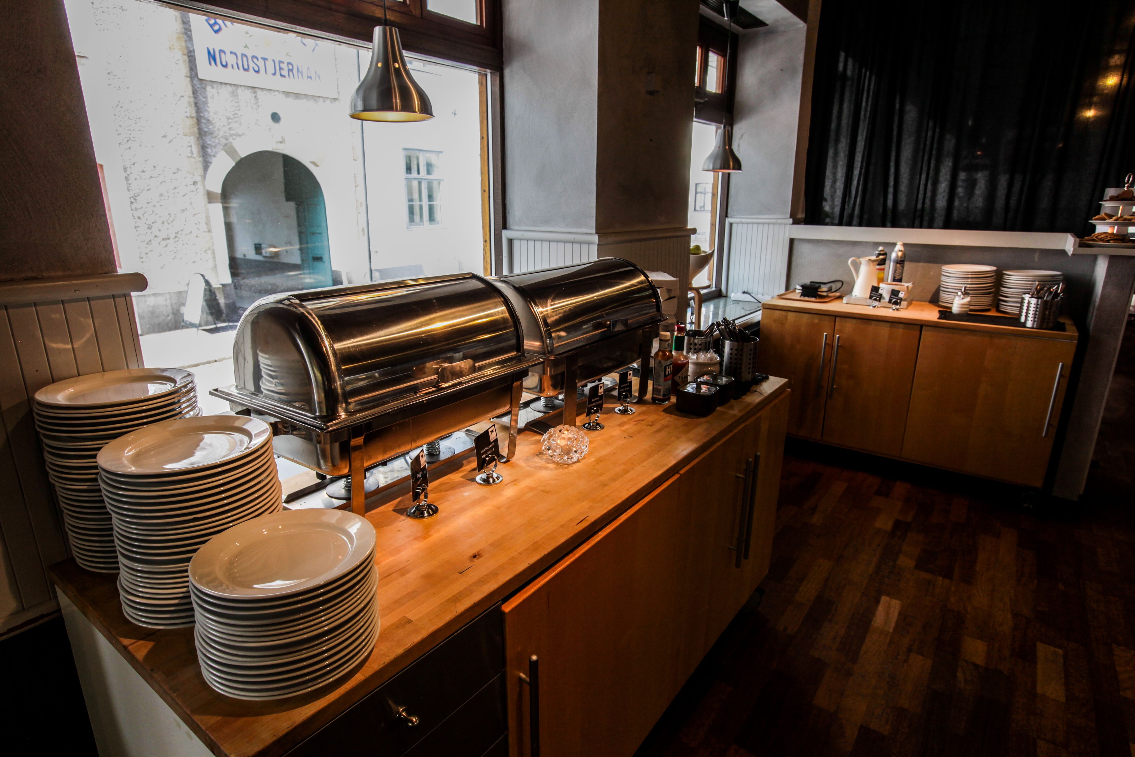 A kitchen area with a stainless steel coffee machine, stacked plates, and a wooden counter.