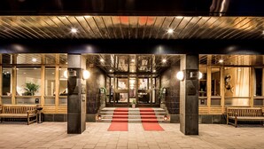 L’entrée d’un hôtel, avec un tapis rouge, des bancs en bois et un design architectural moderne.