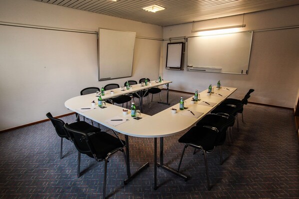 A conference room with a long table, black chairs, and a whiteboard.