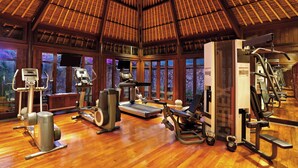 A gym with various exercise equipment, large windows, and a wooden ceiling. - The Oberoi, Lombok (Tanjung)