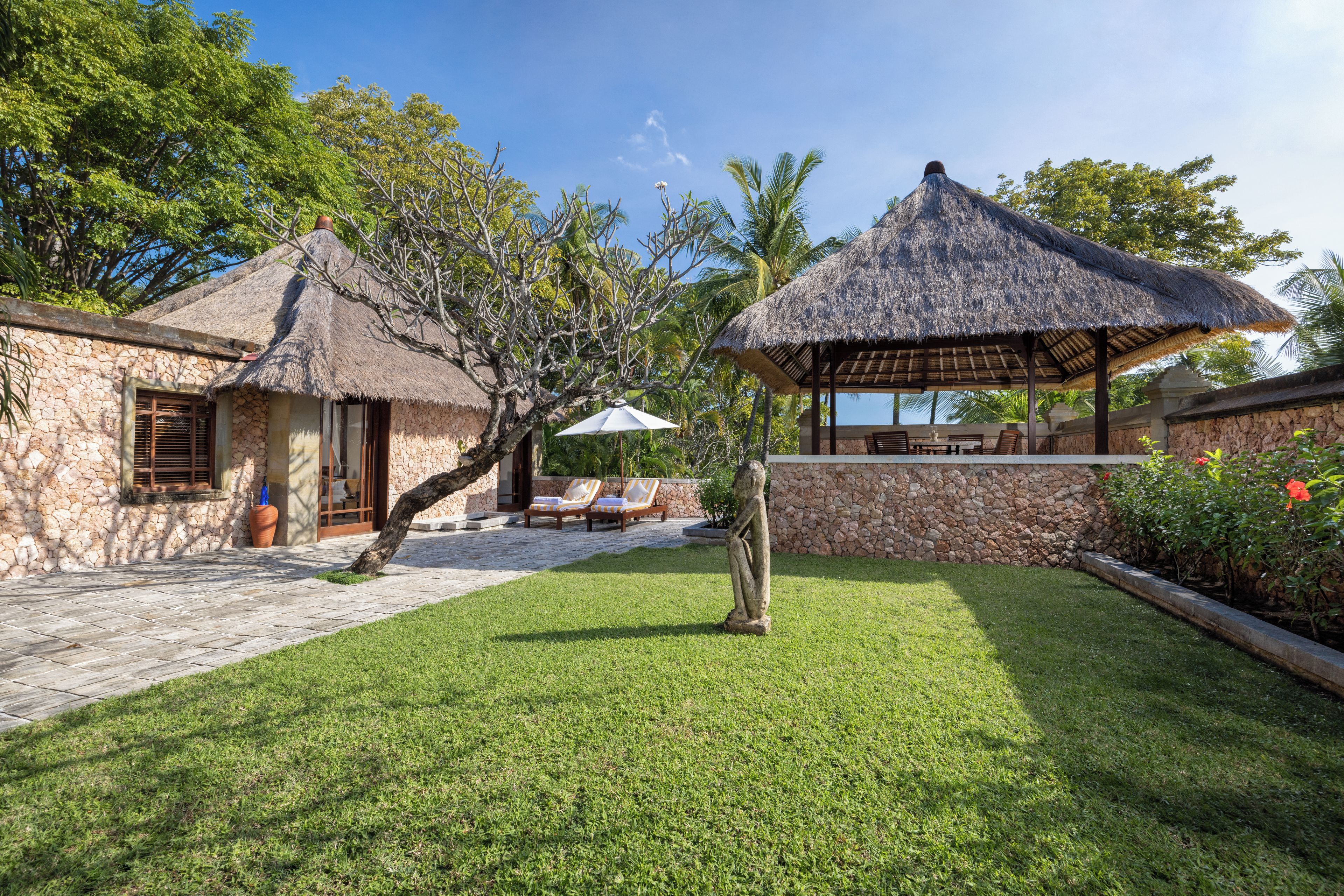 A stone building with a thatched roof, a covered outdoor seating area, and a well-maintained lawn.