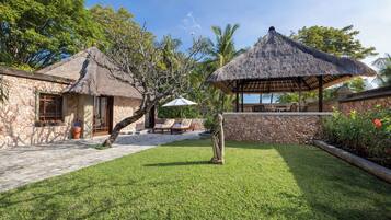 A stone building with a thatched roof, a covered outdoor seating area, and a well-maintained lawn.