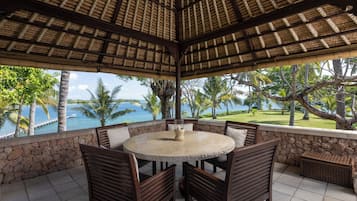 A covered outdoor seating area with a stone wall, a round table, and chairs.