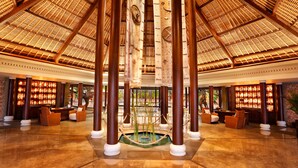 A spacious lobby with high ceilings, large wooden columns, and a central water feature. - The Oberoi, Lombok (Tanjung)