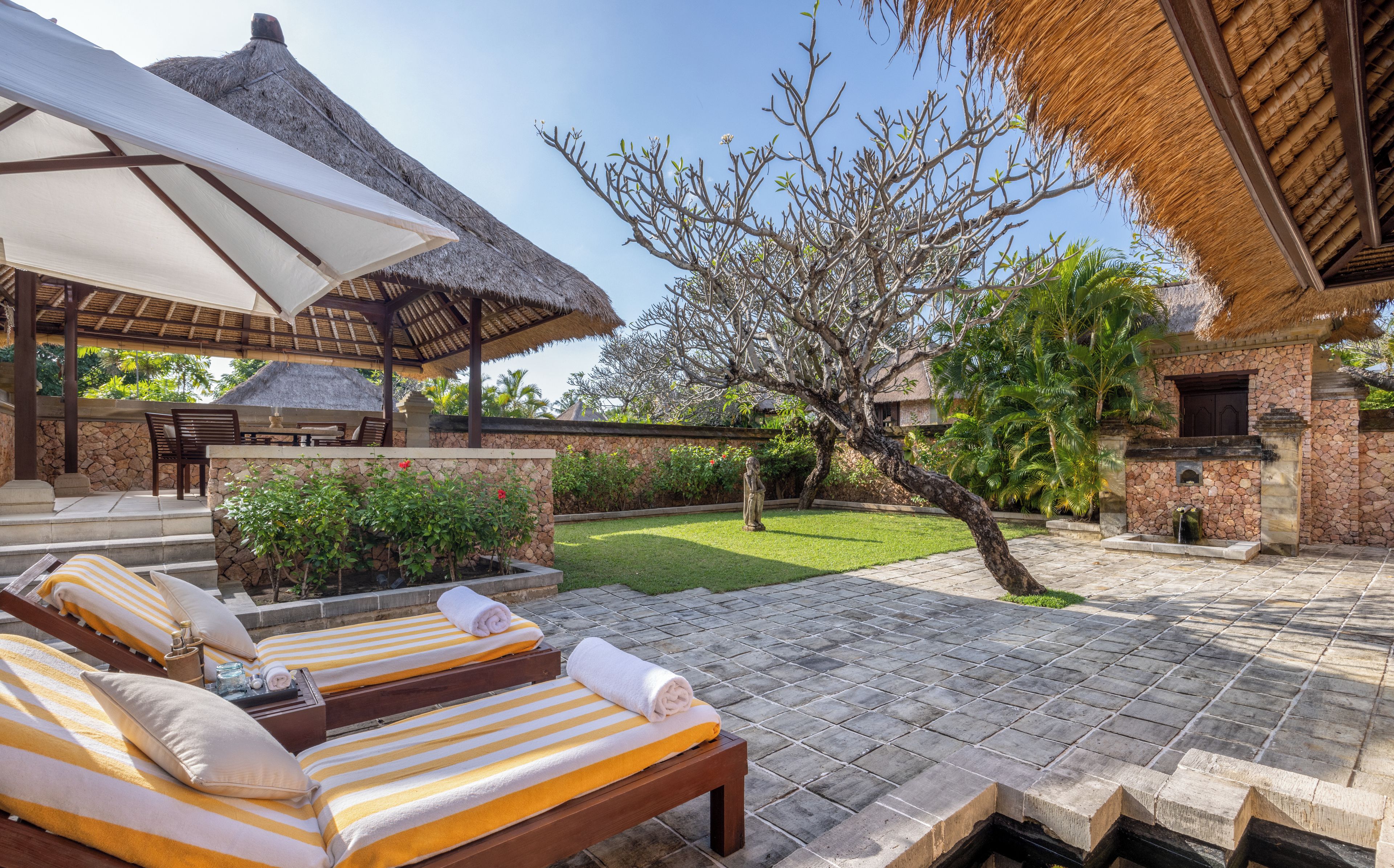 A resort with outdoor seating, a thatched-roof structure, and a stone building.