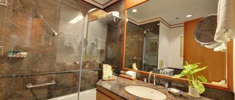 A modern bathroom with a glass-enclosed shower, a marble-tiled wall, a large mirror, and a granite countertop.