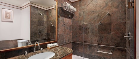 A bathroom with a marble sink, a large mirror, a shower with a glass door, and a bathtub.