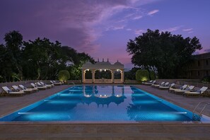 Relax by the serene pool surrounded by lush greenery and shaded seating areas.
