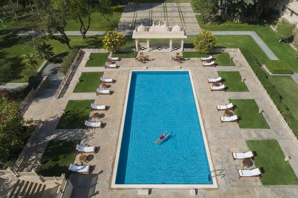 Relax by the rectangular pool surrounded by lounge chairs and a serene gazebo.