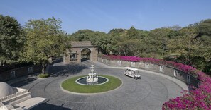 Stroll through the tranquil courtyard, surrounded by lush greenery and vibrant flowers, with a central fountain and golf cart nearby.