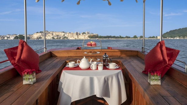 Ein Tisch, gedeckt für ein Nachmittagsteetrinken, auf einem Boot mit Blick auf eine Stadt.