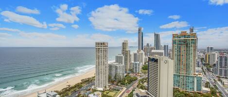 Un paisaje urbano costero con edificios altos, una playa y un cielo azul despejado.