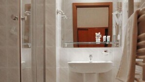 A bathroom with a glass shower enclosure, a sink, and a mirror above it. - Villa Ozone (Sopot)