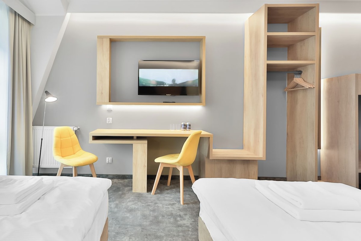 Una habitación de hotel con dos camas, un escritorio, dos sillas, un televisor y un armario.