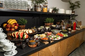Un bufé con diversas opciones de comida, como frutas, ensaladas y pan.