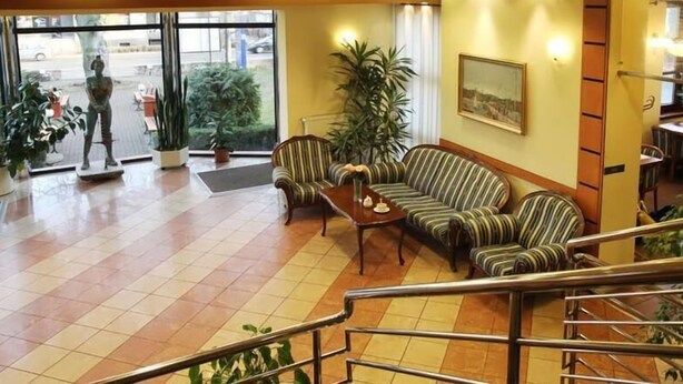 A lobby with striped sofas, a coffee table, and potted plants. - Villa Ozone (Sopot)