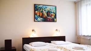 A hotel room with a bed, two bedside lamps, a painting on the wall, and a window with curtains. - Parkhotel Economic (Wielka Wies)