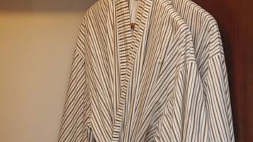A striped robe hanging on a wooden hanger against a wall.