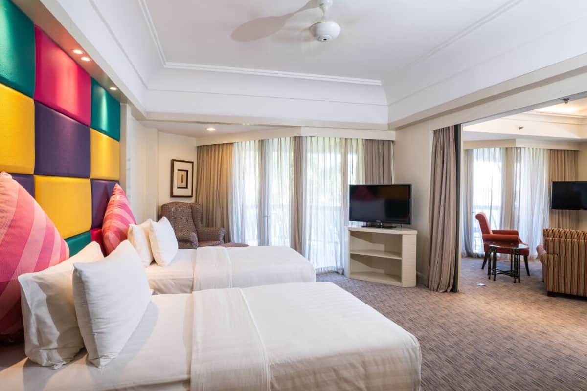 A hotel room with two beds, a TV, a desk, and a sofa.