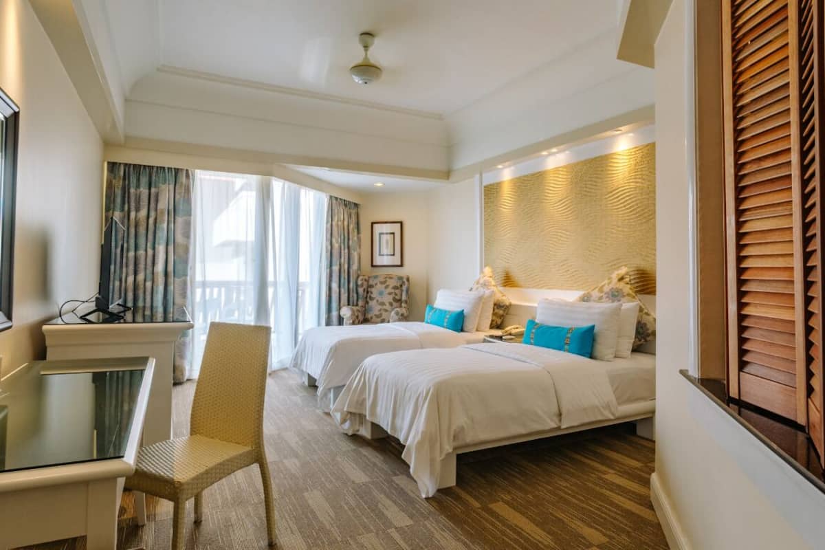 A hotel room with two beds, a desk, and a chair.