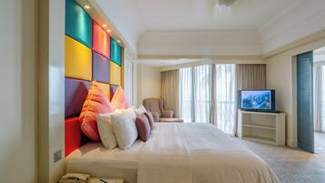A hotel room with a large bed, a television, a chair, and a phone on the side table.