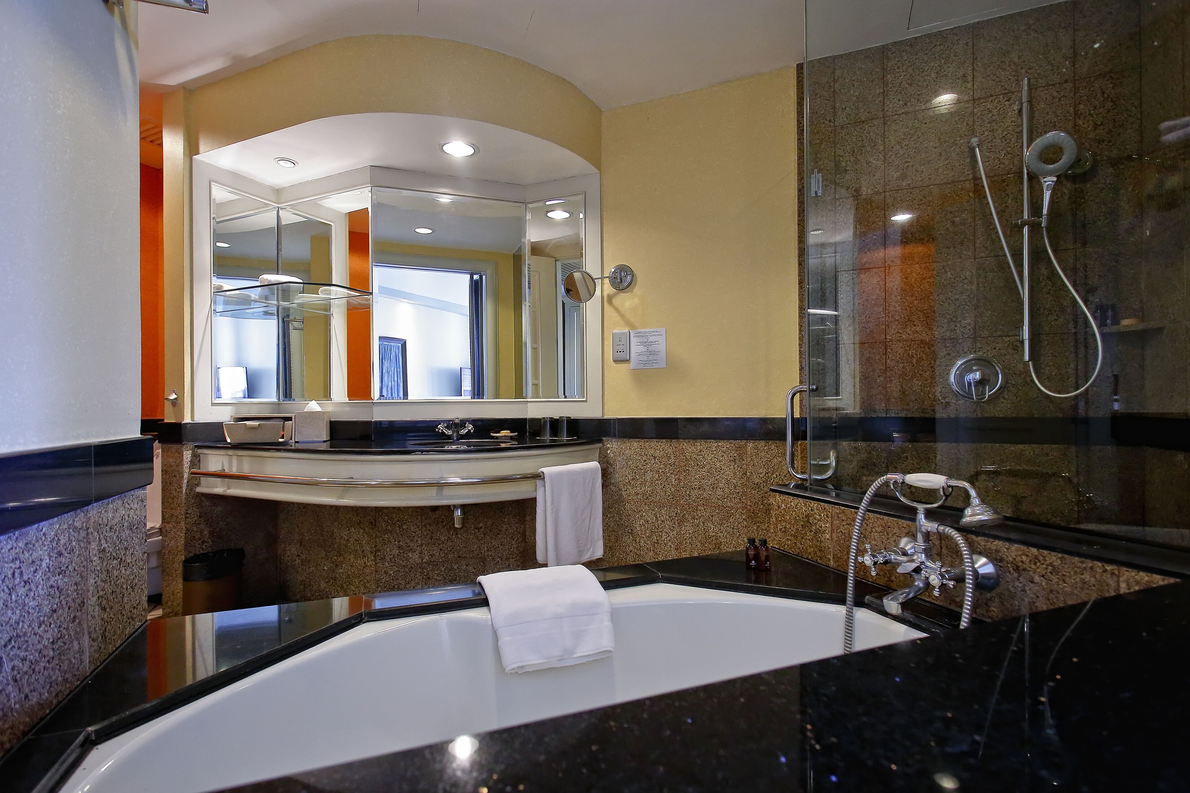 A modern bathroom with a large bathtub, a glass shower enclosure, and a vanity with a mirror.