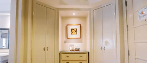 A narrow hallway with a wooden floor, a small table with a coffee maker, and a framed picture on the wall.