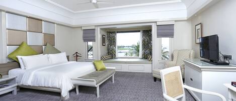 Ein Hotelzimmer mit Bett, Schreibtisch, Stuhl, Fernseher und einem Fenster mit Vorhängen.
