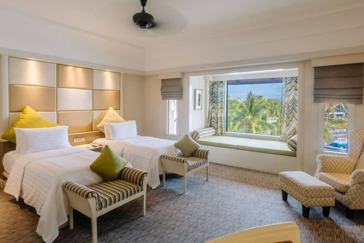 A hotel room with two beds, a seating area, and a large window with a view.