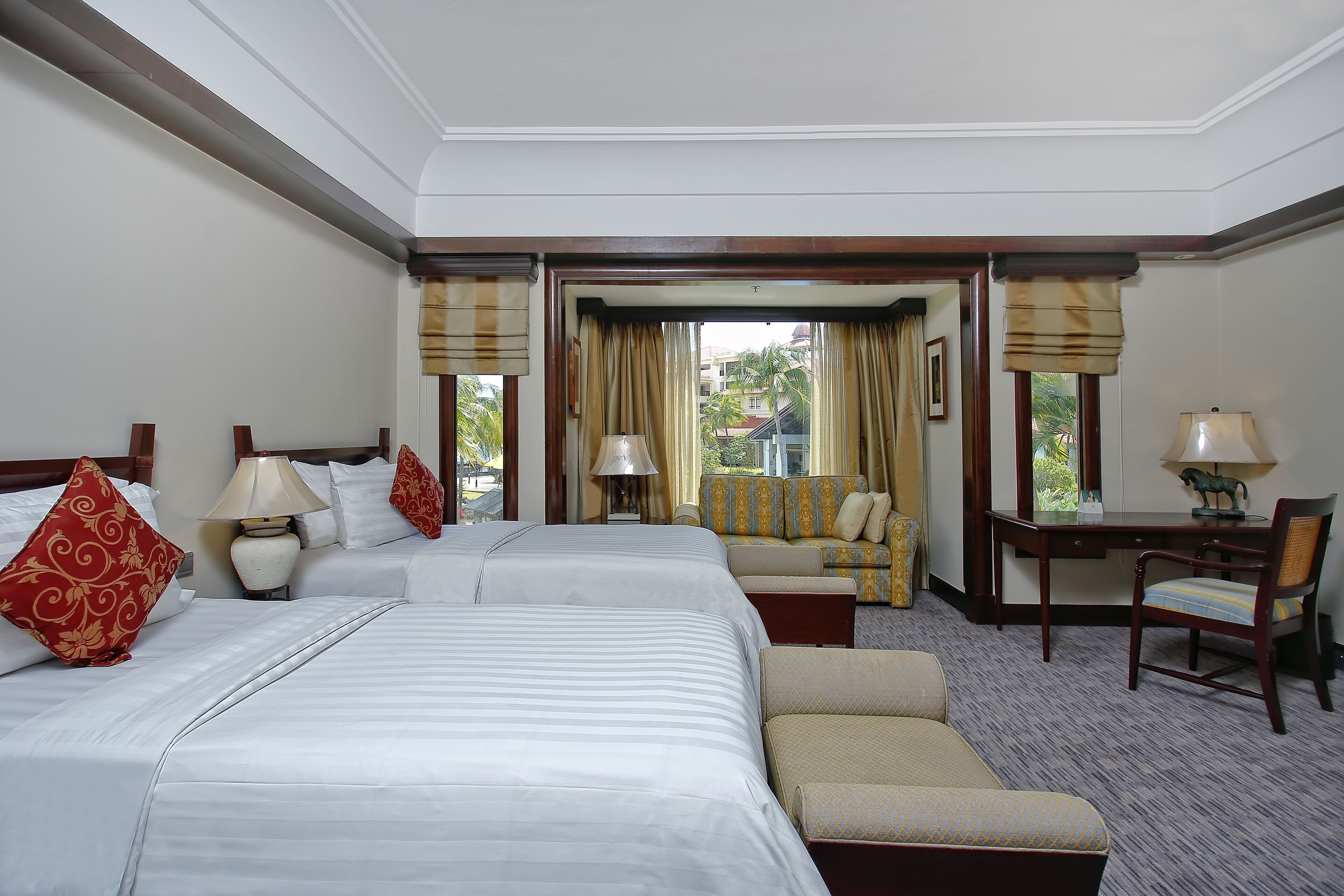 A hotel room with two beds, a sofa, a desk, and a chair.