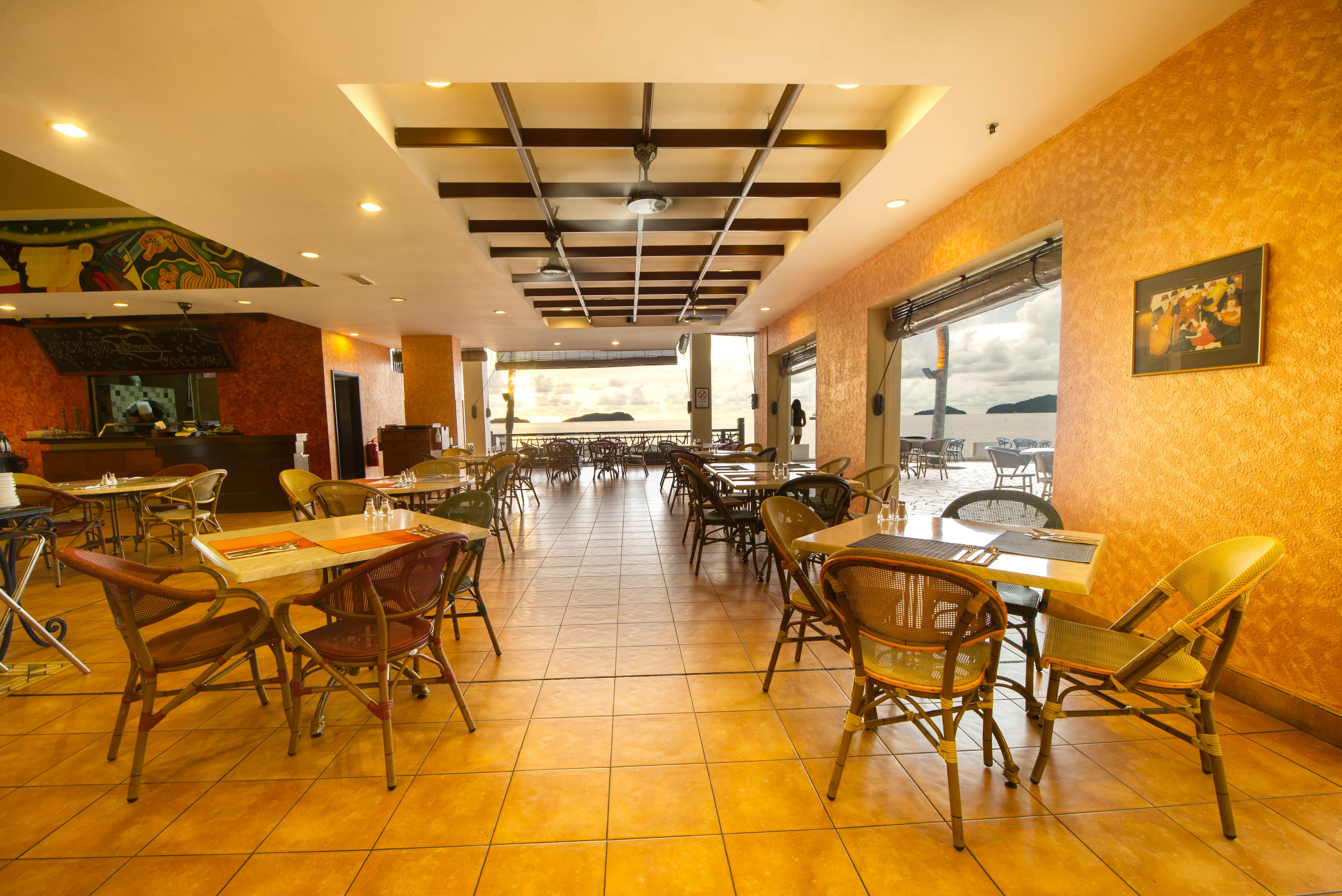 A spacious restaurant with high ceilings, tiled floors, and wicker chairs.