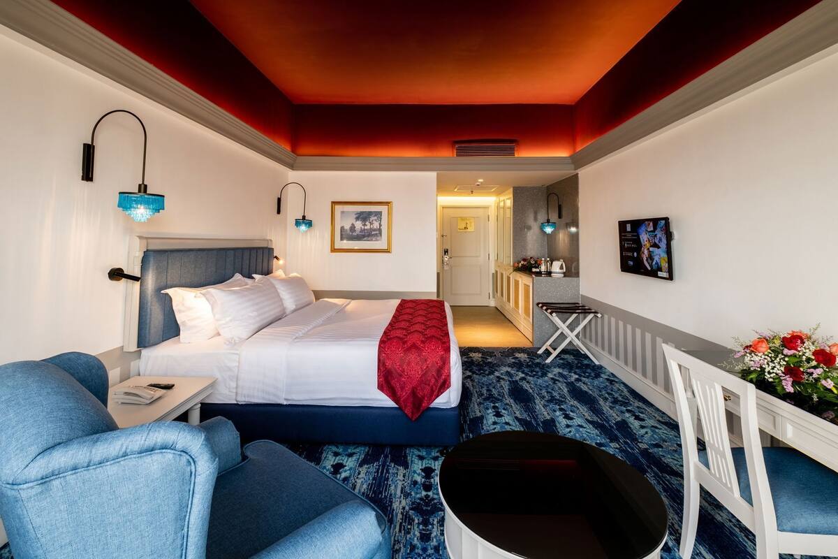 Una habitación de hotel con una cama, un escritorio, una silla, una mesita y un radiador.