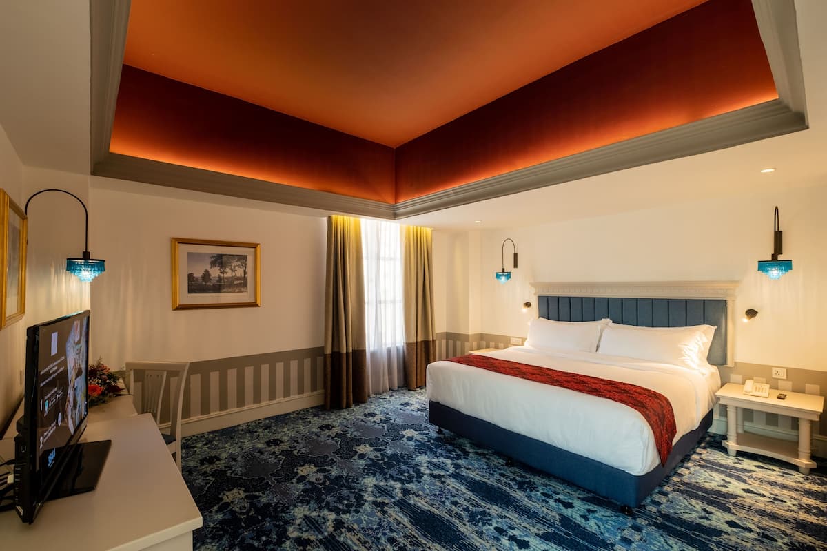 Una habitación de hotel con una cama grande, un escritorio con una computadora y un televisor.