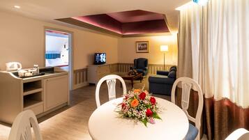 Una habitación de hotel moderna con comedor, televisión, sofá y candelabro.