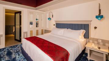 A hotel room with a large bed, a nightstand with a phone, and a bathroom visible through an open door.