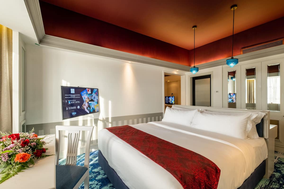 Habitación de hotel con una cama grande, un televisor en la pared y un escritorio con una silla.