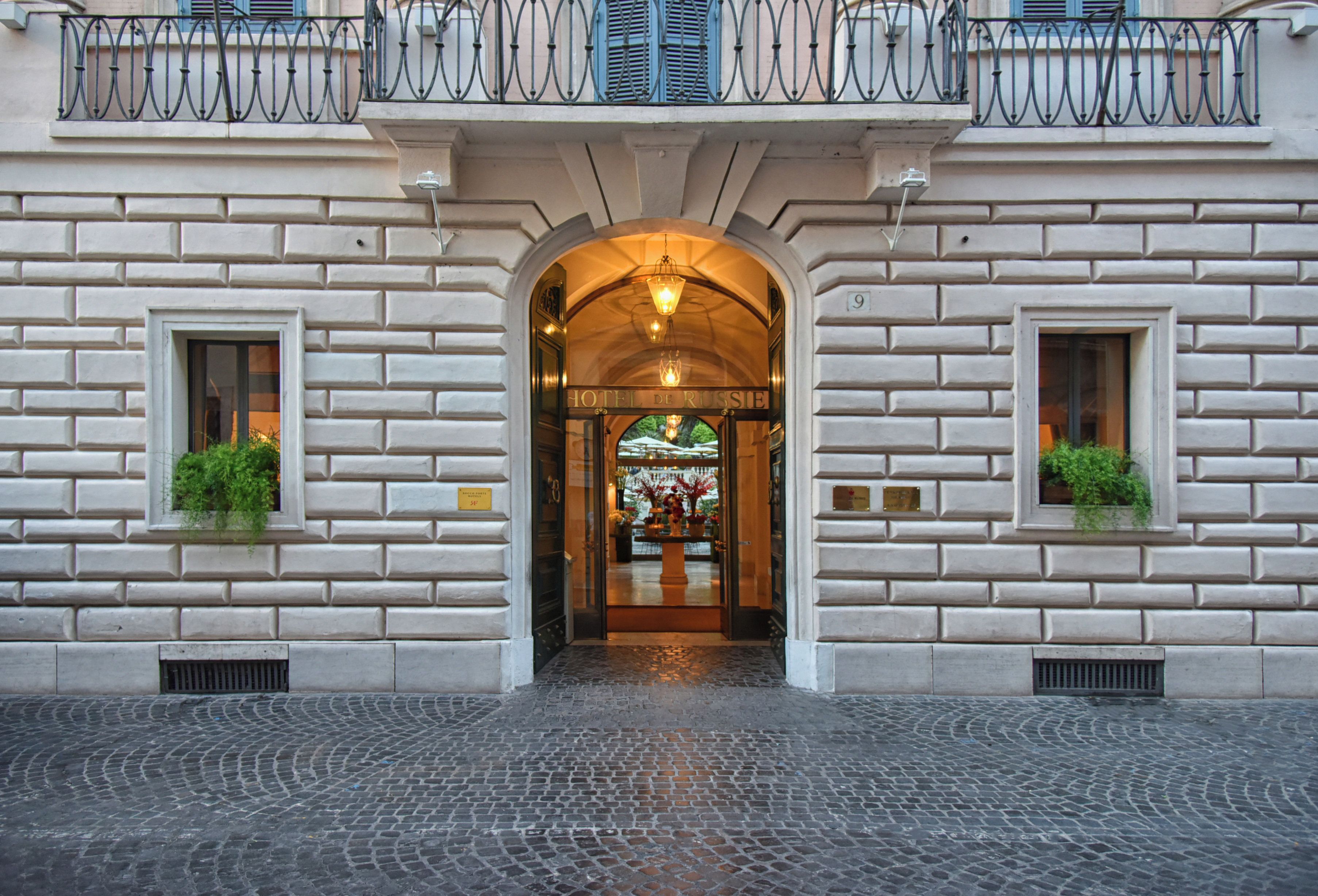 A hotel entrance with a stone facade, an arched doorway, and a sign above the door.
