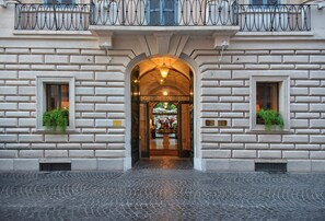 A hotel entrance with a stone facade, an arched doorway, and a sign above the door.