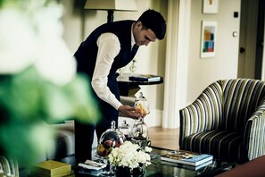 A person arranging a table with a glass dome, a vase of flowers, and a book.