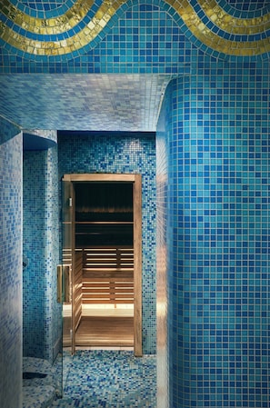 A hallway with blue mosaic tiles and a wooden bench.
